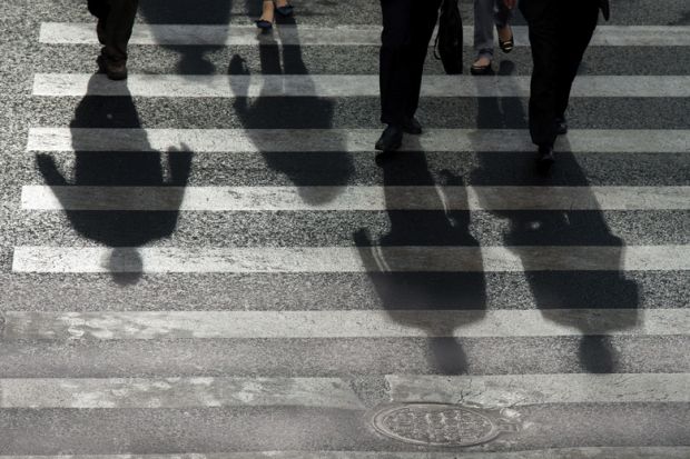 People's shadows cast on road crossing