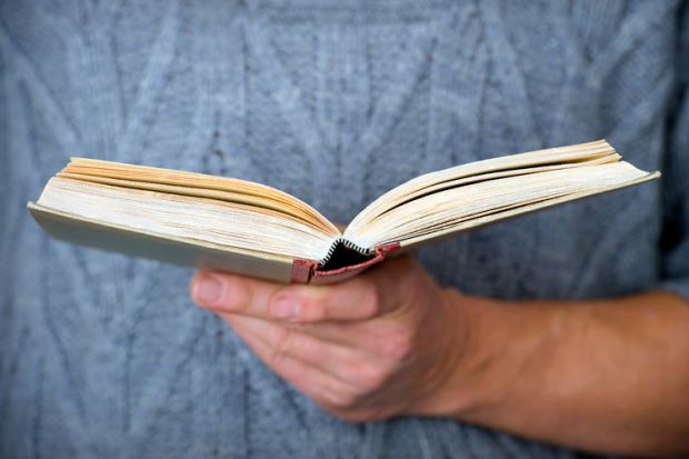 Person holding open book in hand