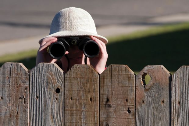 Person looking over fence with binoculars