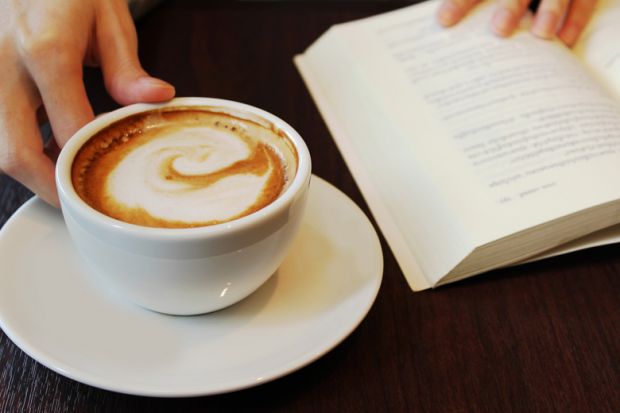 Person reading book and drinking coffee