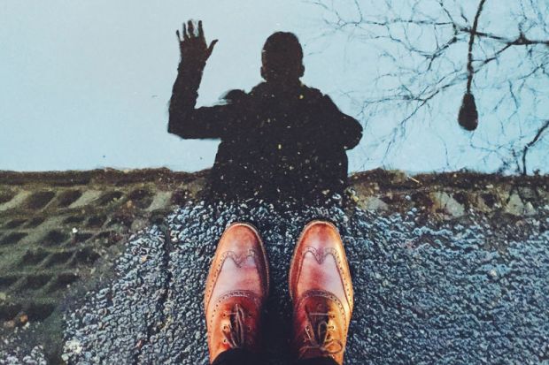 person waving at reflection in street puddle