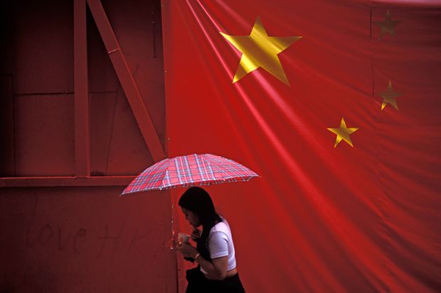 A large banner Chinese flag hangs over a pedestrian under an umbrella. To illustrate that there is ‘little universities can do’ to stop Beijing interference. A large banner Chinese flag hangs over a pedestrian under an umbrella. To illustrate that there is ‘little universities can do’ to stop Beijing interference.
