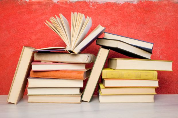 Pile of books against red wall