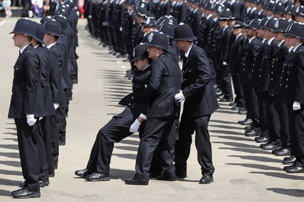 A police officer is caught by colleagues as he becomes faint during a Passing out Parade for the Metropolitan Police. To illustrate how the assessment burden is causing students to wilt