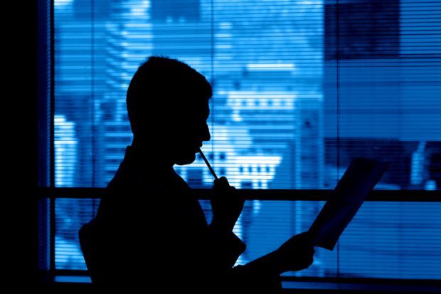 A reviewer in a corporate office ponders a manuscript