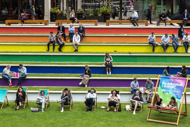 People sit on steps painted in the rainbow flag colours in support of Pride, Paddington, London. To illustrate that the public still supports EDI work in UK universities.
