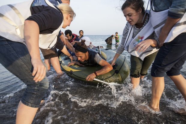 Kos, Greece - October 2015: Volunteers give a hand to migrants from Afghanistan who arrived at Kos from Turkey on a dinghy Kos, Greece - October 2015: Volunteers give a hand to migrants from Afghanistan who arrived at Kos from Turkey on a dinghy