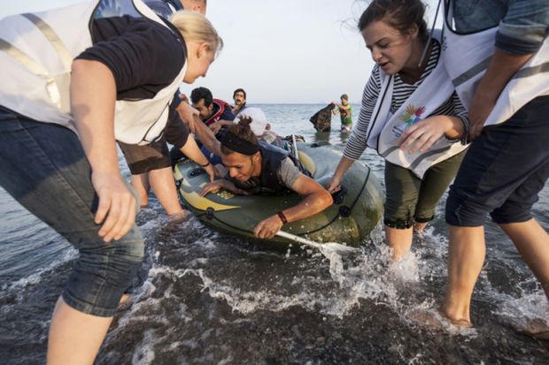 Kos, Greece - October 2015: Volunteers give a hand to migrants from Afghanistan who arrived at Kos from Turkey on a dinghy