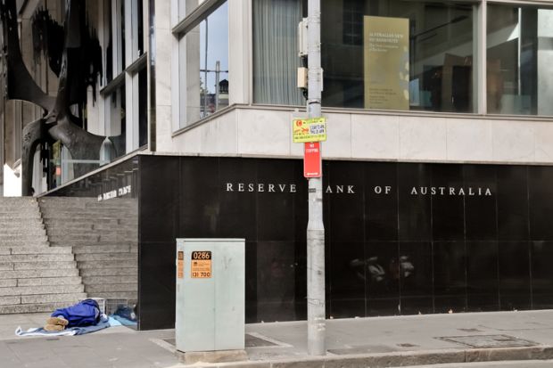Reserve Bank of Australia name on black granite wall in Sydney Australia with a homeless man sleeping nearby