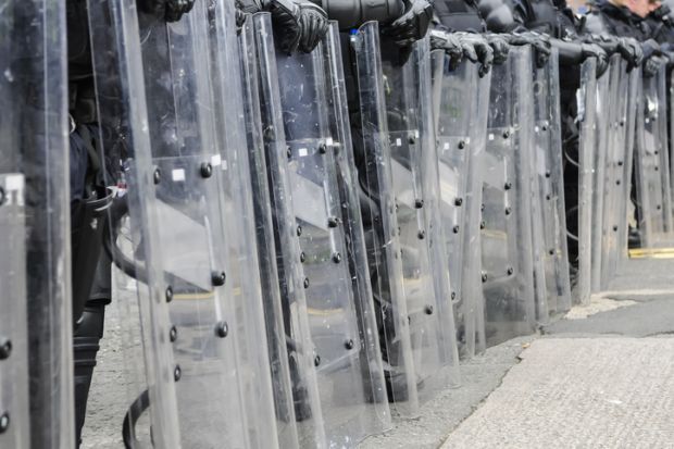 Police with riot shields illustrating the threat to higher education in Myanmar