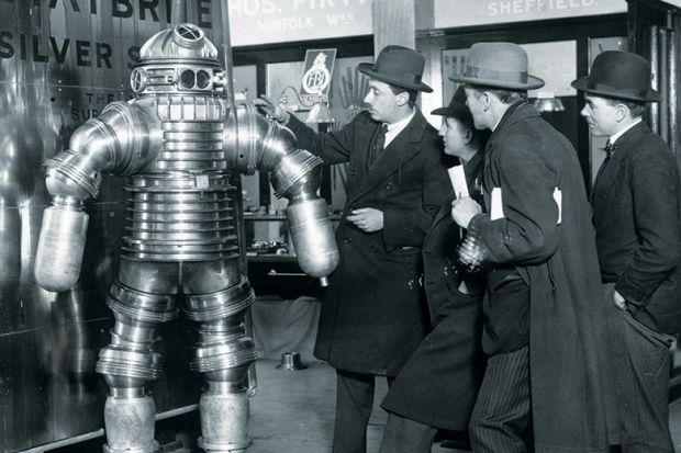 Men examining 1950s-style robot Men examining 1950s-style robot