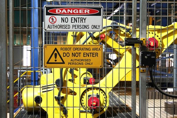 Warning signs outside a robotic assembly line, symbolising restrictions on AI use in research 