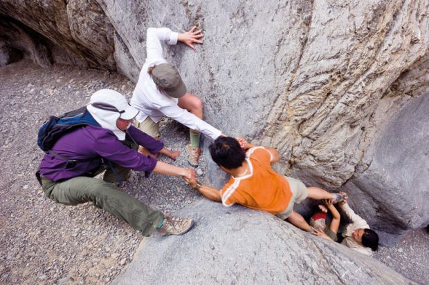 Rock climbers helping man overcome obstacle