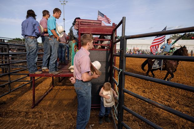  A boy listens to the playing of the national anthem with a group of rodeo participants before the rodeo, USA. To illustrate how university networks in rural areas could bridge social divides.
