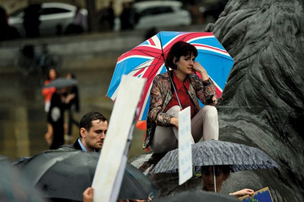 Sad woman with Union flag umbrella in rain at Trafalgar Square
