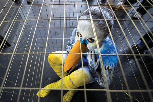 Sad young woman dressed as bird in cage Sad young woman dressed as bird in cage
