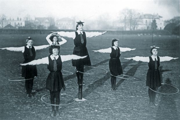 schoolgirls balancing a ball and plate on their heads while spinning a hoop