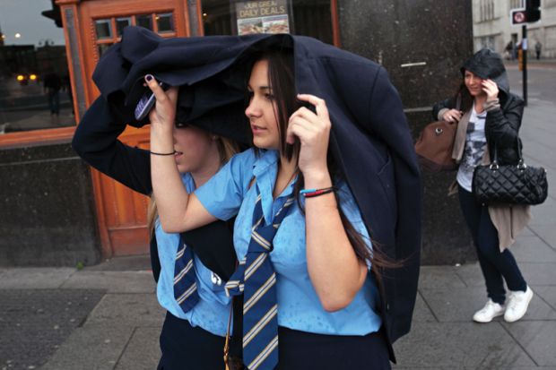 Schoolgirls shelter heads from rain, Liverpool Schoolgirls shelter heads from rain, Liverpool