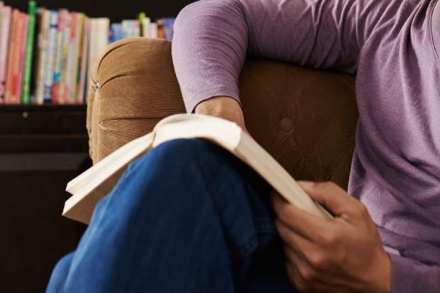 seated-man-on-sofa-reading-book.jpg