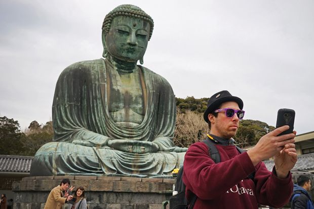 Man taking a selfie in front of a Buddha