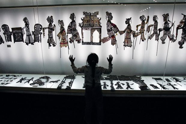 A visitor admires shadow puppets made of leather during an exhibition. China A visitor admires shadow puppets made of leather during an exhibition. China