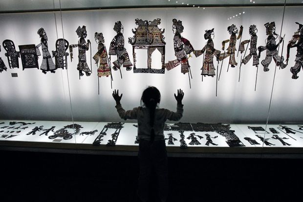 A visitor admires shadow puppets made of leather during an exhibition. China