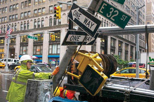 A private contractor replaces a traffic signpost with a newer version in New York City, illustrating change of direction in America