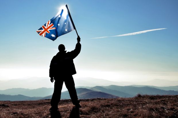 Silhouette of man waving Australian flag on hilltop