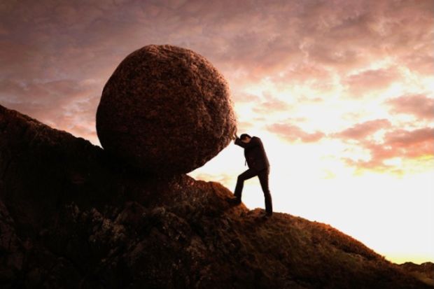 A businessman rolls a rock up a hill like Sisyphus