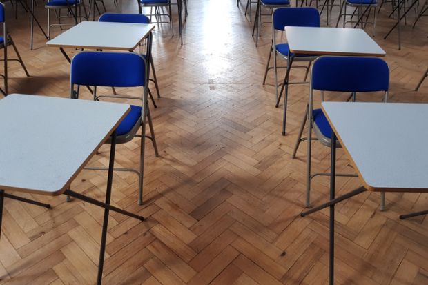 Small white exams desks in a hall