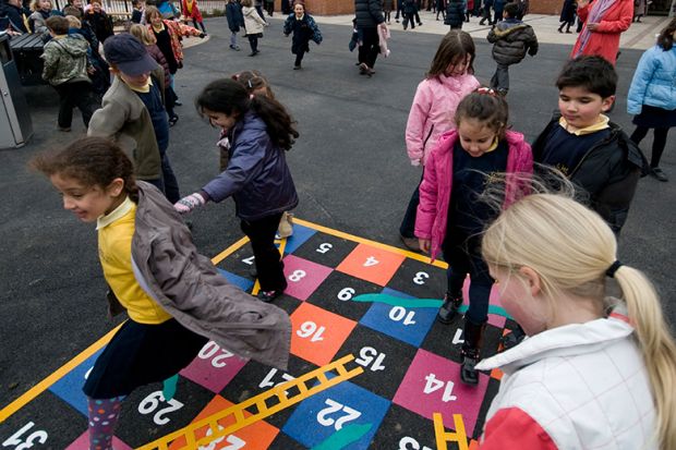 Children playing snakes and ladders in a school playground. To illustrate that the channelling of government funding into charity at the expense of universities has yet to be proven.