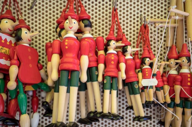 Sorrento, Italy - June 12, 2017 Painted wooden marionette dolls of the figure of Pinocchio in a souvenir shop in Sorrento. Italy. Pinocchio's long nose symbolised a lie.