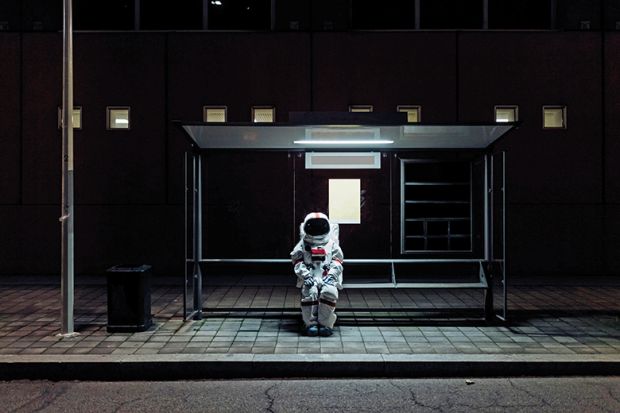 An astronaut sits at a bus stop to illustrate being left behind