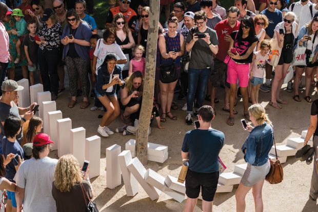 Spectators watch large domino pieces collapse