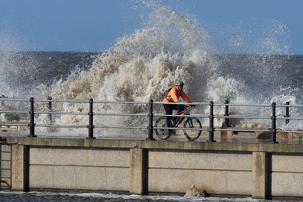 Man riding bicycle on stormy pier