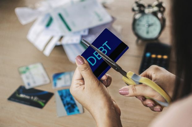 Scissor cut through a credit card marked "debt"