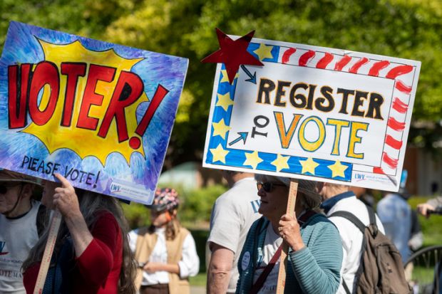 People with signs encouraging people to vote