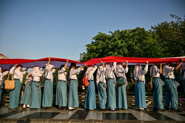 Students unfurl a long flag in Indonesia's national colours as they parade through the streets during a ceremonial event to mark Indonesia's 80th Independence Day in Surabaya on 17 August, 2025.