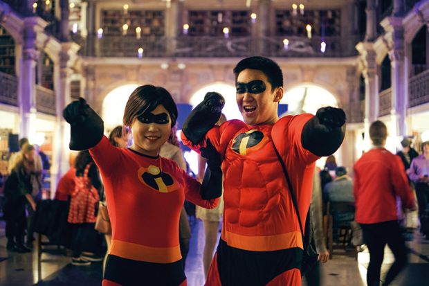 A male and female pose in matching costumes featuring characters from the film The Incredibles