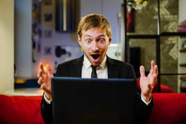 Surprised happy businessman wearing black suit using laptop amazed with open mouth for surprise