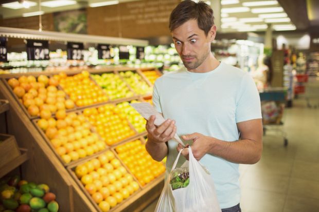 Surprised man reading receipt in grocery store