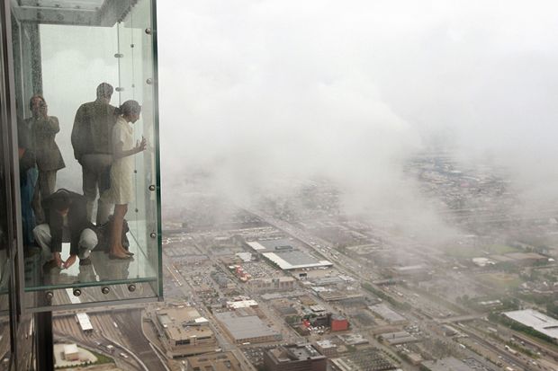 Visitors stand out on the Ledge, a glass cube that juts out from the 103rd floor Skydeck of the Sears Tower, Chicago