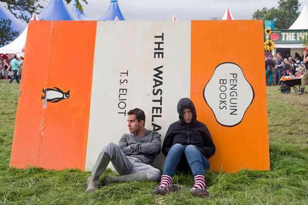 People sitting against a giant book cover of The Wasteland by T.S. Eliot. To illustrate that the number of academics working in under-fire departments such as English and modern languages in UK universities fell to a record low last year.