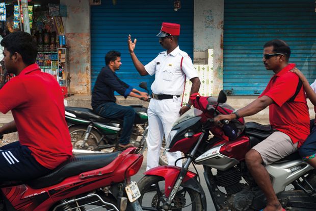 Policeman directing traffic on a street at Puducherry, India
