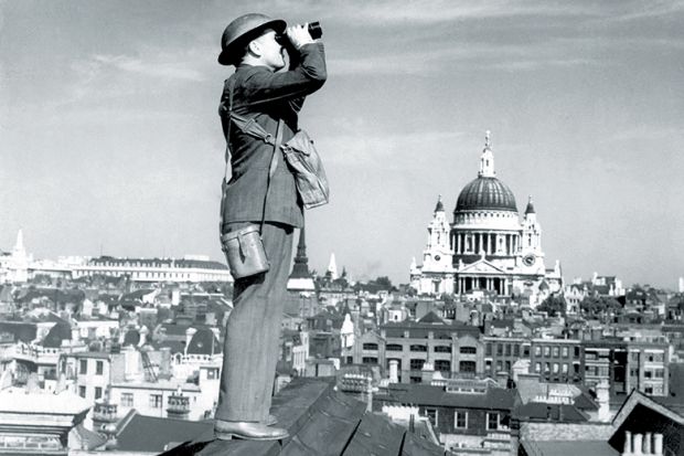 Man standing on a roof using binoculars