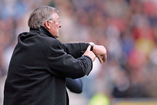 Alex Ferguson, manager of Manchester United, points to his watch