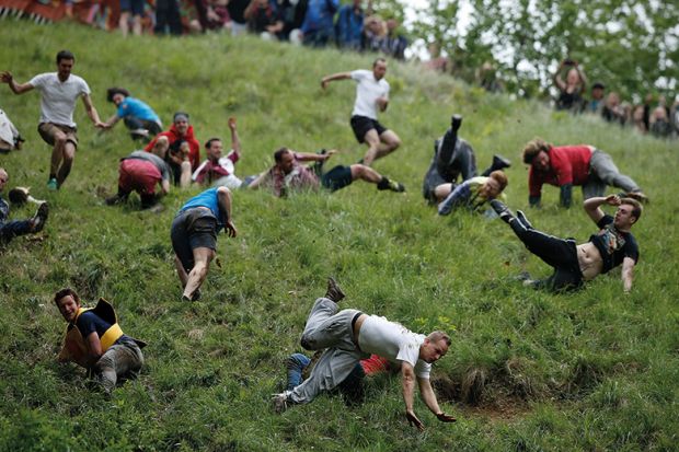 Competitors tumble down Coopers Hill in pursuit of a round Double Gloucester cheese during an annual cheese rolling competition