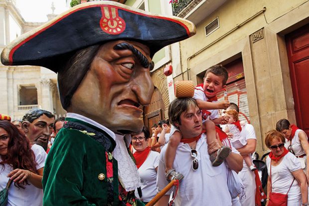 A child react (R) as Caravinagre 'Vinegar face' kiliki (C) approaches during the Comparsa de Gigantes y Cabezudos, or Giants and Big Heads parade on the third day of the San Fermin Running of the Bulls festival on July 8, 2016 in Pamplona, Spain. 