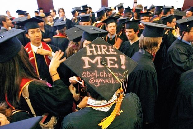 Graduating student displays a Hire me sign written on his mortar board