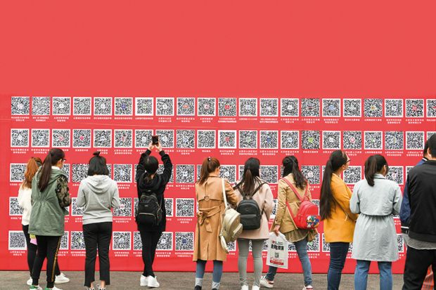 Students in China take pictures of QR codes at a jobs fair